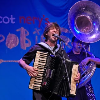 Scot Nery playing the accordion and singing on stage at Boobietrap